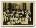 Original title:  Margaret Addison in centre of group of students, in common room, Annesley Hall. Image courtesy of Victoria University Archives (Toronto, Ont.).