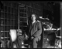 Original title:  Glass negative (black and white); portrait of John Ojijatekha Brant-Sero, a Mohawk loyalist, seated inside a study, wearing a three piece suit; bookcases, a desk, a ladder and a chair are behind him; Canada.  Photographic process