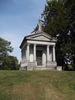Original title:  Sanford Mausoleum. After Jackson Sanford's death from tuberculosis in 1897, Senator Sanford engaged the New York City firm of C.E. Tayntor & Co. to design a mausoleum for his son, and for future use by the family. Built of Vermont granite, it was rumoured to cost $100,000. The Senator's remains were the first to be placed here, in 1899, to be followed by Jackson Sanford, and his infant son Harry Vaux Sanford, who had died in 1872. This mausoleum is located in the Hamilton Cemetery. Photo by Paul Grimwood, used with permission.